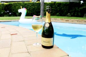 a bottle of wine and a glass next to a pool at Midrand Bed and Breakfast in Midrand