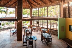 a restaurant with tables and chairs and windows at Pousada Iguana in Canoa Quebrada