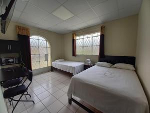 a bedroom with two beds and a desk and two windows at Kira's House in Piura