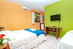 a hotel room with two beds and a tv at Pousada Iguana in Canoa Quebrada +57 photos