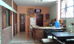 a kitchen with a bar with a refrigerator and tables at Hostal Casa Taisha in Montañita