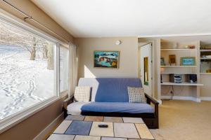 Habitación con silla azul y ventana grande. en Trailside Retreat, en Warren