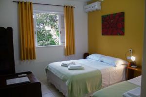 a bedroom with two beds and a window at Pousada GaropaSul in Garopaba