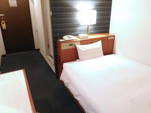 una camera d'albergo con letto, lampada e telefono di Smile Hotel Towada a Towada Altre 17 foto