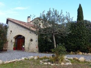 un edificio in pietra con una porta rossa e un albero di Le Mas de Crieulon a Saint-Jean-de-Crieulon