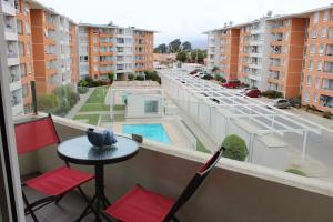 balcón con mesa, sillas y vistas a la ciudad en Aparthotel Serena, en La Serena