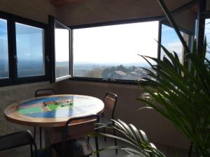 una mesa y sillas en una habitación con ventanas en Gîtes La Tour le Mas de Crieulon en Saint-Jean-de-Crieulon