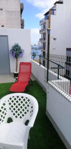 a red chair and a table on a balcony at Alcaravaneras Hostel in Las Palmas de Gran Canaria