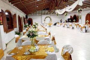 um grande salão de banquetes com mesas e cadeiras brancas em Hotel Alto de los Andaquies em San Agustín