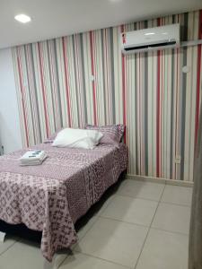 Dormitorio pequeño con cama con manta morada en Kitnet 1 mobiliada no centro de Torres a 600m da Praia Grande, en Torres