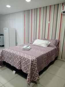 1 dormitorio con 1 cama con manta morada en Kitnet 1 mobiliada no centro de Torres a 600m da Praia Grande, en Torres