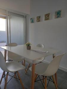 una mesa de comedor blanca y sillas con una planta en Complejo Pirovano, en Lincoln