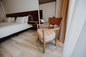ein Schlafzimmer mit einem Bett, einem Stuhl und einem Schreibtisch in der Unterkunft La Urumpta Hotel by AKEN Mind in Río Cuarto