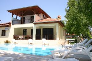 a swimming pool with white chairs and a house at Begonville Villa in Koycegiz