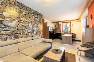 a living room with a couch and a stone wall at Boutique Apartment in Kukucka Residences in Tatranská Lomnica