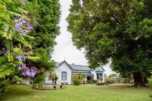 a blue house with trees in the yard at Karamana Homestead (1872) in Coromandel Town