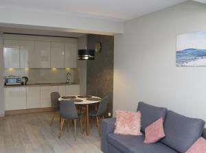 eine Küche und ein Wohnzimmer mit einem Sofa und einem Tisch in der Unterkunft Apartament Czarna Góra S26 in Heudorf