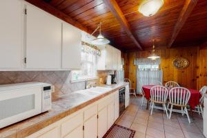 a kitchen with white cabinets and red chairs at Maul Cabin in Shaver Lake