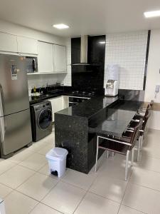 uma cozinha com um balcão preto e electrodomésticos em aço inoxidável em Flat Extraordinário Beira Mar em Porto de Galinhas com pé na areia Cupe Beach Living em Porto de Galinhas