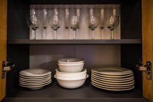 a cabinet filled with plates and wine glasses at Allegro in Liepāja