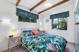 a bedroom with a bed and two windows at Waimea Cottage - Waikanae Holiday Home in Waikanae