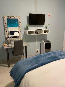 sypialnia z łóżkiem i biurkiem z telewizorem w obiekcie Seven Wonders B&B w mieście Port Shepstone