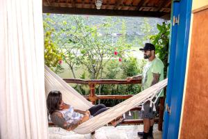 un homme et une femme dans un hamac sur une terrasse couverte dans l'établissement Pousada Recanto da Chapada, à Mucugê