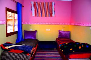 two beds in a room with pink and purple walls at Gîte Tamsoulte in Imlil