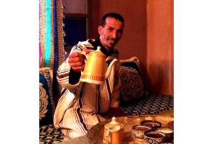 Un uomo seduto su una sedia con una tazza di tè di Gîte Tamsoulte a Imlil