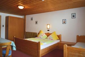 een slaapkamer met een houten bed met gele kussens bij Pension Leitenhof in Niederau