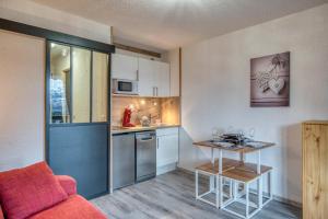 une petite cuisine avec un canapé rouge et une table dans l'établissement Studio Cosy coin-nuit proche centre - Vue splendide, à Saint-Gervais-les-Bains