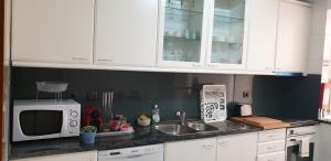 ヴィラ・ノヴァ・デ・ガイアにある3doorsDownの白いキャビネット、シンク、電子レンジ付きのキッチンが備わります。