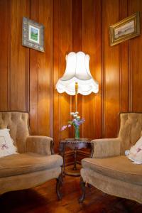 a living room with two chairs and a lamp at Karamana Homestead (1872) in Coromandel Town