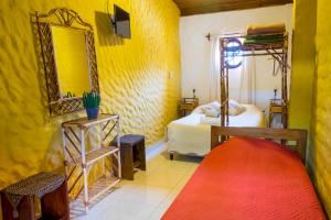 a yellow room with a bed and a mirror at La Montaña in Cafayate