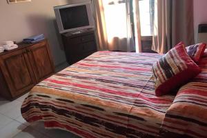 1 dormitorio con 1 cama y TV en Departamento ALUMA, en San Rafael