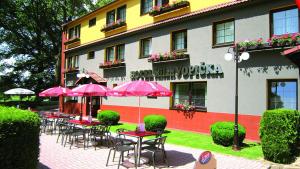 a patio area with tables, chairs, umbrellas and umbrellas at Hotel Milan Vopicka in Hluboká nad Vltavou