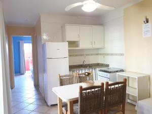 cocina con mesa y nevera blanca en Residencial Natux, en Bombinhas