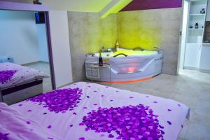 a bedroom with a tub and a bed with purple flowers at Apartmani Tajna in Paraćin