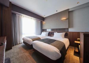 福岡市にあるホテルトラッド博多のベッド2台と窓が備わるホテルルームです。