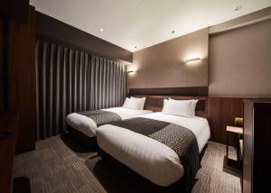 a hotel room with two beds and a window at Hotel Trad Hakata in Fukuoka