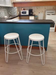 two white stools sitting in front of a kitchen counter at The Comfort Cottage on Williams in Broken Hill