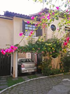 un'auto parcheggiata di fronte a una casa con fiori rosa di Casa 12 Búzios Vilas a 500m da Rua das Pedras, top localização em condomínio lindo e calmo, portaria 24h a Búzios