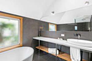 a bathroom with a tub, sink, and mirror at Seahaven Village in Barwon Heads