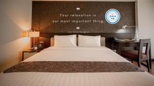 een hotelkamer met een bed en een bureau met een bord bij Lily Hotel Bangkok in Bangkok