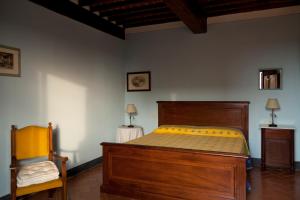 1 dormitorio con cama de madera y silla en Agriturismo La Colombaia, en Cerreto Guidi