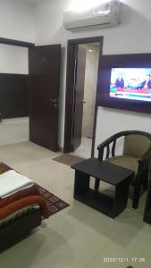 een kamer met een spiegel, een stoel en een tv bij Hotel Popular in Amritsar