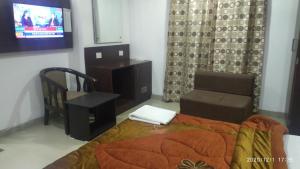 - une chambre avec un lit, une chaise et une télévision dans l'établissement Hotel Popular, à Amritsar