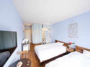 a bedroom with two beds and a flat screen tv at Hotel Shionnoumi in Miyako-jima +18 photos