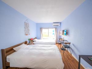 宮古島にあるホテル しおんの海の青い壁の客室で、ベッド2台、窓が備わります。
