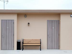 a bench in front of a building with two doors at Hotel Shionnoumi in Miyako-jima